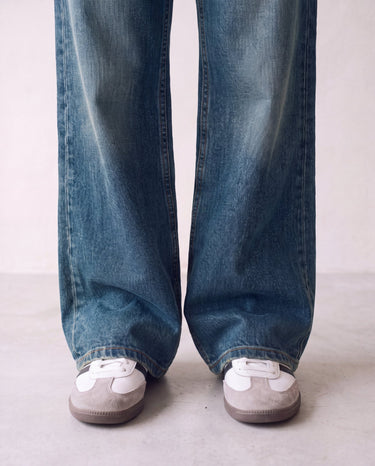 Harlow Low Rise Jeans in washed blue — close-up of the wide hems pooling over sneakers