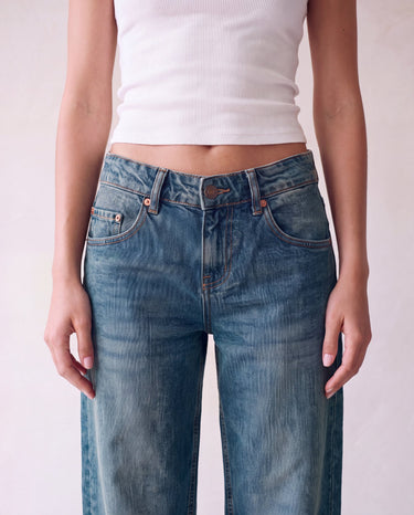 Harlow Low Rise Jeans in washed blue — close-up of the low-rise waistband, button fly and rivets