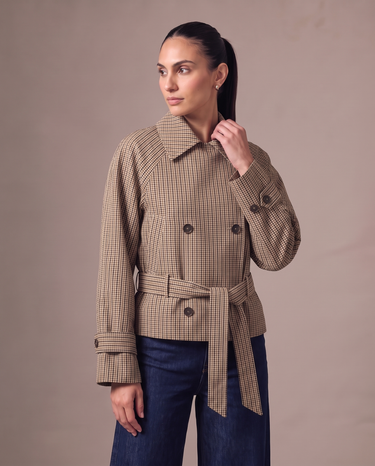 Lorelai Trench Coat in brown check — front view, short double-breasted coat with a self-tie belt, worn over dark indigo wide-leg jeans