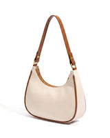 The Ines Crescent Bag in cream with tan trim, studio hero view showing the half-moon silhouette and shoulder strap