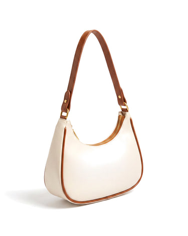 The Ines Crescent Bag in cream with tan trim, three-quarter rear view showing the strap keeper