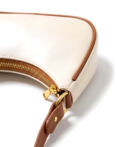 Close-up of the Ines Crescent Bag's gold-tone top zip and tan leather trim