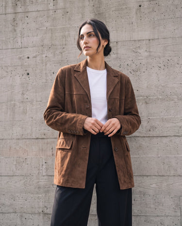 Model wearing the dark brown Isla Faux Suede Jacket open over a white tee and black trousers, front view