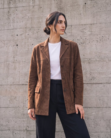 Side view of the dark brown Isla Faux Suede Jacket worn over a white tee and wide-leg black trousers