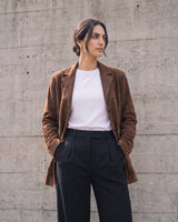Model standing with hands in pockets wearing the dark brown Isla Faux Suede Jacket, front view