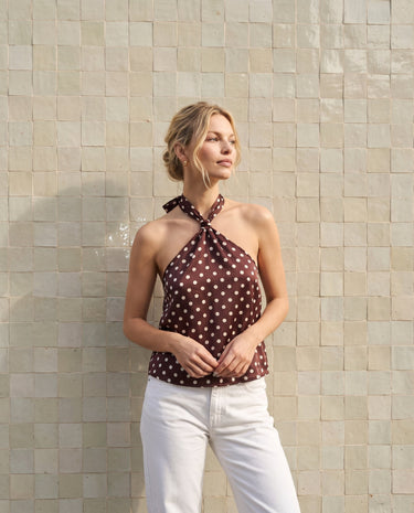 Isola Halter Neck in brown polka dot — full-length front view on model against a tiled wall