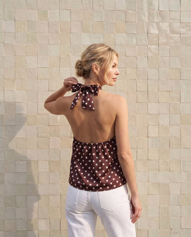 Isola Halter Neck in brown polka dot — back view on model showing the open back and neck tie