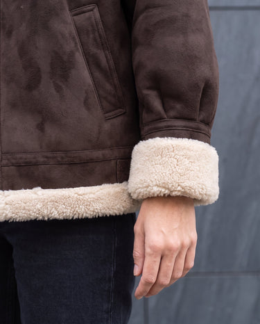 Detail of the Leni Suede Vintage Coat's pocket and shearling-trimmed cuff in dark brown suede-look fabric