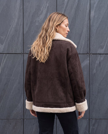 Back view of the dark brown Leni Suede Vintage Coat with cream shearling collar and hem trim