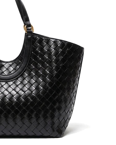 Close-up of the Lucca Woven Tote's glossy basketweave texture and handle attachment in black