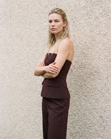 Model with arms crossed wearing the brown structured strapless top, three-quarter view – Moriel Heritage
