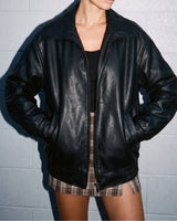 Model wearing the black Marseille Faux Leather Jacket open over a black top, close front view