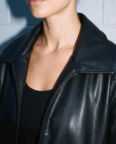 Close-up of the Marseille Faux Leather Jacket's spread collar and zip pull in black