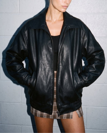 Model wearing the black Marseille Faux Leather Jacket open over a black top, close front view