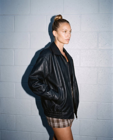 Model in the black Marseille Faux Leather Jacket, three-quarter view showing the dropped shoulder