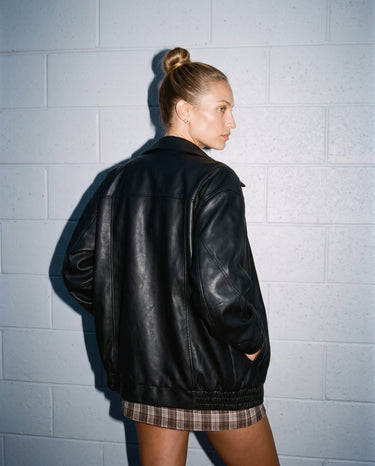 Back-side view of the oversized black Marseille Faux Leather Jacket on model