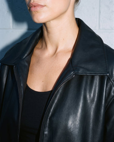 Close-up of the Marseille Faux Leather Jacket's spread collar and zip pull in black