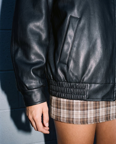 Detail of the Marseille Faux Leather Jacket's welt pocket and ribbed elasticated hem in black