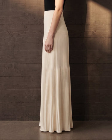 Side view of the ivory Matilde Skirt showing the clean hip line and the fluid drape of the pleats to the floor