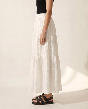 The Noemi A-Line Skirt in white — tiered maxi skirt, side view on model