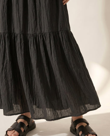 The Noemi A-Line Skirt in black — tiered maxi skirt, walking view on model