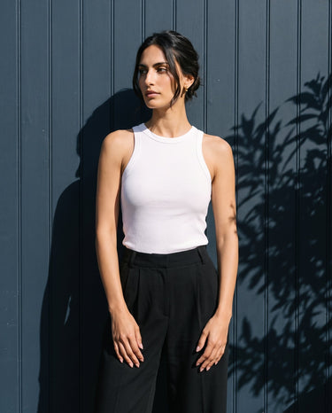 Model wearing the white ribbed cotton tank against a dark panelled wall, front view – Moriel Heritage