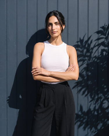 Model with arms crossed wearing the white ribbed cotton tank – Moriel Heritage