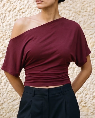 Odile Tee in burgundy — three-quarter view showing the dolman sleeve and gathered side
