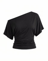 Odile Tee in black — asymmetric off-shoulder draped knit top with dolman sleeves, flat-lay