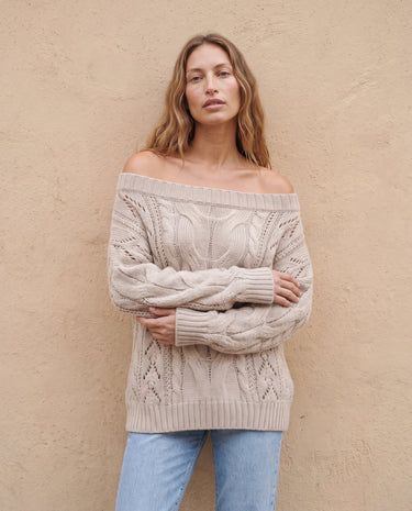 The Off Shoulder Cable Knit Sweater in khaki — off-shoulder cable-knit sweater, front view with arms crossed on model