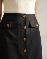 Close-up of the black Elegant Retro Slimming Skirt showing the wide waistband, tortoiseshell-effect buttons and the two flap patch pockets at the hip