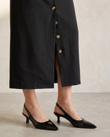 Detail of the lower half of the black Elegant Retro Slimming Skirt showing the buttons down to the hem and the open front slit, styled with black slingback heels