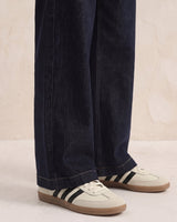 Close-up of dark denim jeans showing the wide leg drape and hem over trainers – Moriel Heritage