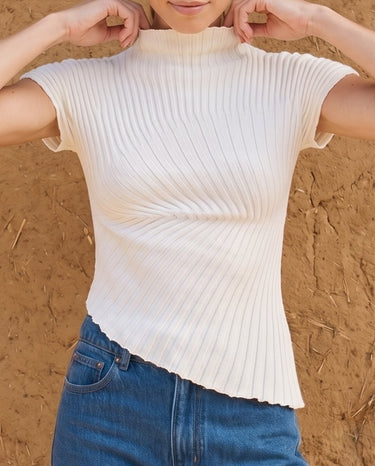 Rivelle Knit in cream white — front view with arms raised, showing the diagonal rib
