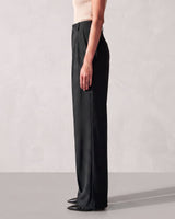 Side view of the black Riviera Tailored Pants showing the clean side seam and the wide leg falling to the floor
