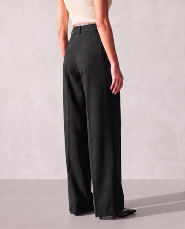 Back three-quarter view of the black Riviera Tailored Pants showing the fit through the hip and the wide leg