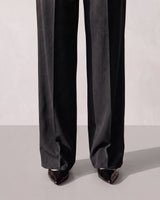 Detail of the lower leg of the black Riviera Tailored Pants showing the pressed crease and full-length hem over pointed heels