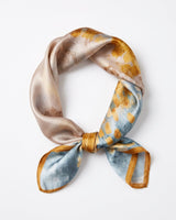 Satin Scarf in golden watercolour — champagne, blue and amber tones with gold border, tied, flat lay on white