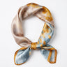 Satin Scarf in golden watercolour — champagne, blue and amber tones with gold border, tied, flat lay on white