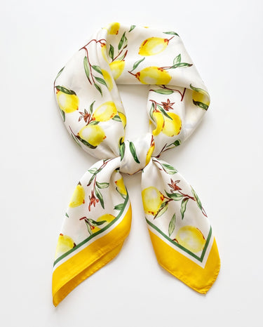 Satin Scarf in lemon print — white silky scarf with watercolor lemons and yellow border, tied, flat lay on white