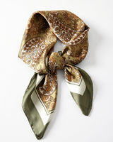 Satin Scarf in olive paisley — olive green and gold paisley print, tied in a knot, flat lay on white