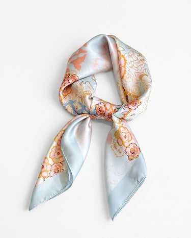 Satin Scarf in powder blue floral — pale blue silky scarf with peach and gold florals, tied, flat lay on white