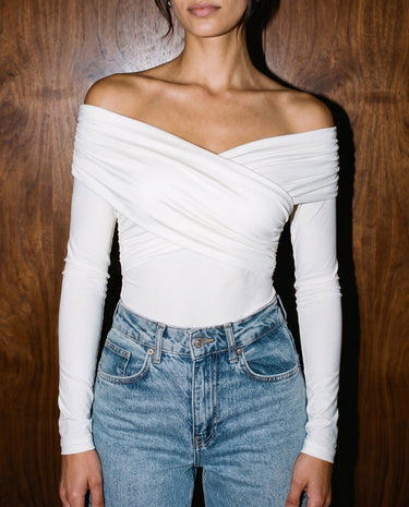 Model wearing white off-shoulder bodysuit with blue jeans, cropped front view – Moriel Heritage