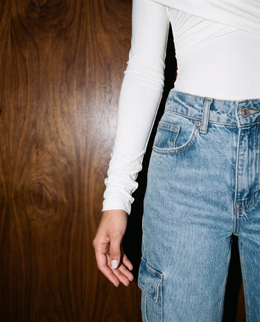 Close-up of white bodysuit showing long ruched sleeve and fitted waist – Moriel Heritage