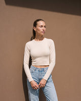 Model wearing beige long-sleeve crew-neck top with blue jeans, full front view – Moriel Heritage