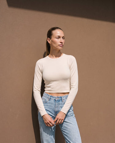 Model wearing beige long-sleeve crew-neck top with blue jeans, full front view – Moriel Heritage