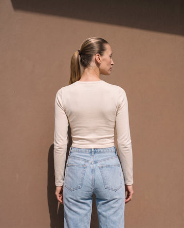 Model wearing beige long-sleeve crew-neck top, back view – Moriel Heritage