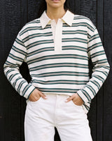 Stripe Long Sleeve Polo in green — front view with hands in pockets against a dark wall