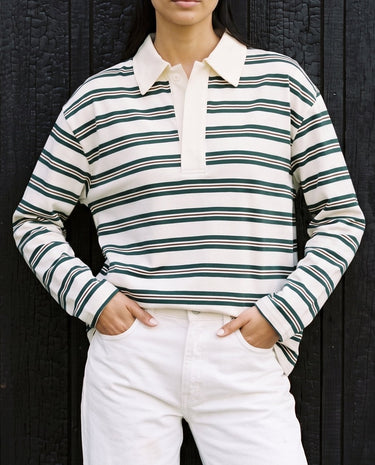 Stripe Long Sleeve Polo in green — front view with hands in pockets against a dark wall