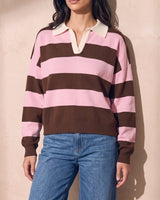 Striped Knit Polo Sweater in pink and cocoa — model leaning on sunlit plaster wall, relaxed styling